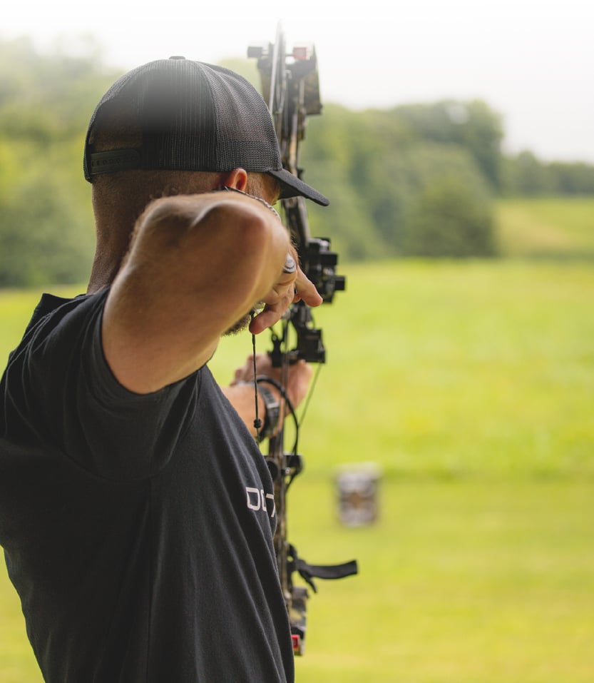 A man draws his bow and aims at a target.